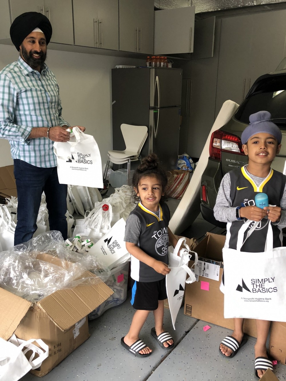Baljeet Singh, Trustee and Parent, prepares hygiene kits with his sons for delivery to Simply the...